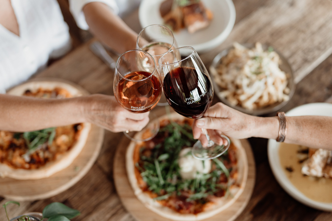 Wine glasses being toasted above food at Phillip Island Winery