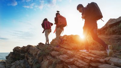 Young asian couple climbing up on the mountain,hiking and team work concept.