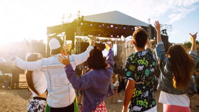 Young happy friends drinking beer and having fun at music festiv